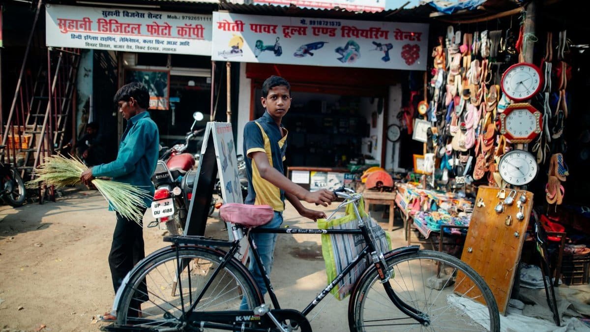 Teen boy with bicycle in a vibrant urban market showcasing local shops and street vendors.