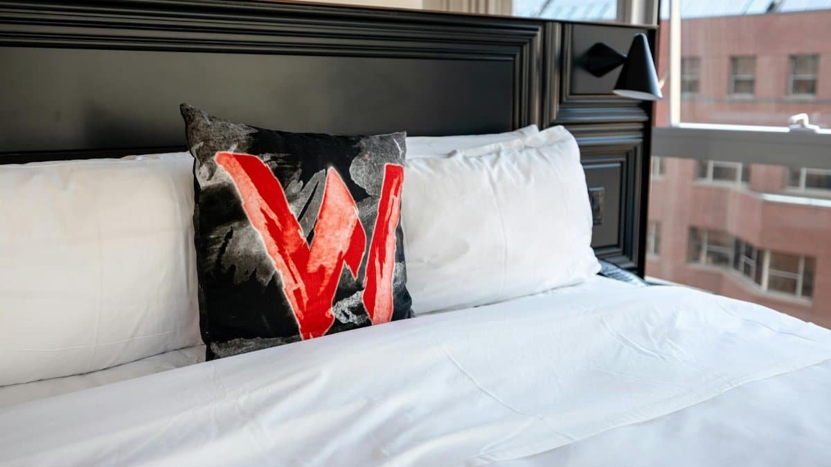 Elegant bedroom in Boston featuring a stylish bed with a bold decorative pillow and city view.