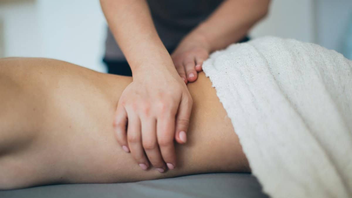 Close-up of a woman receiving a therapeutic massage in a serene spa setting with a white towel.