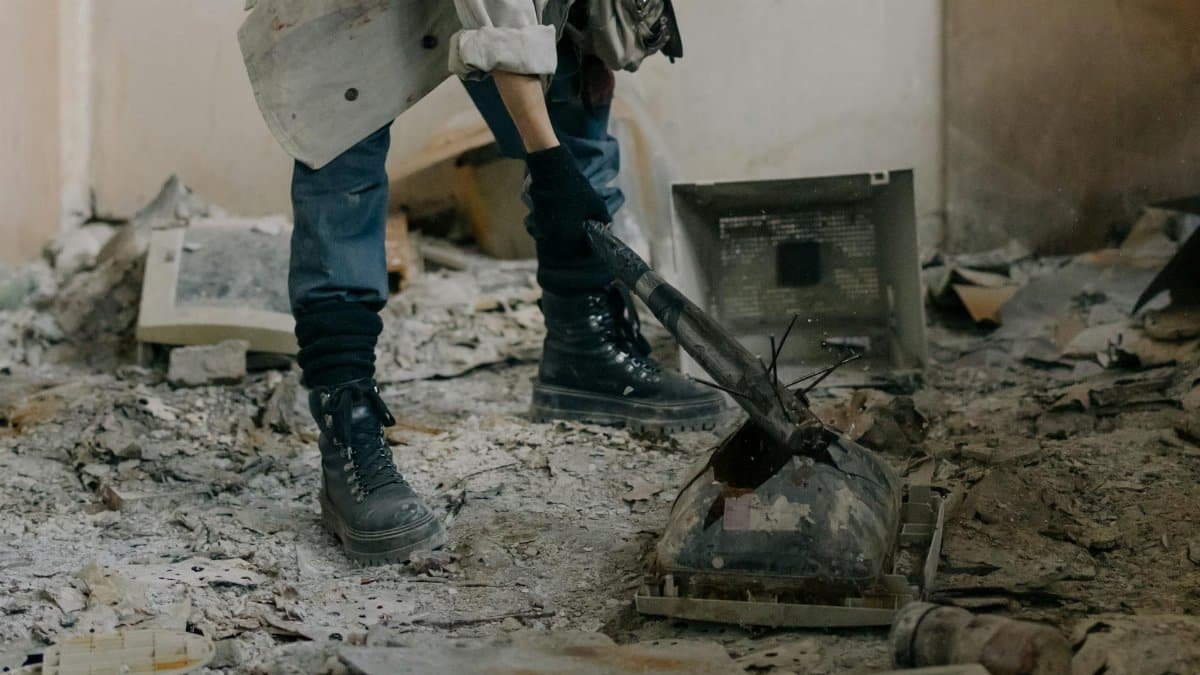 Rugged individual breaking outdated electronics in a derelict, dusty interior.