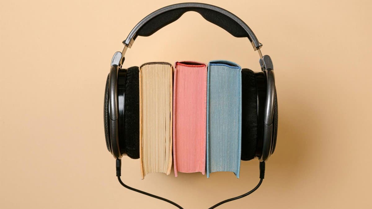 Stylish conceptual image of headphones and books on a beige background, symbolizing audiobooks.