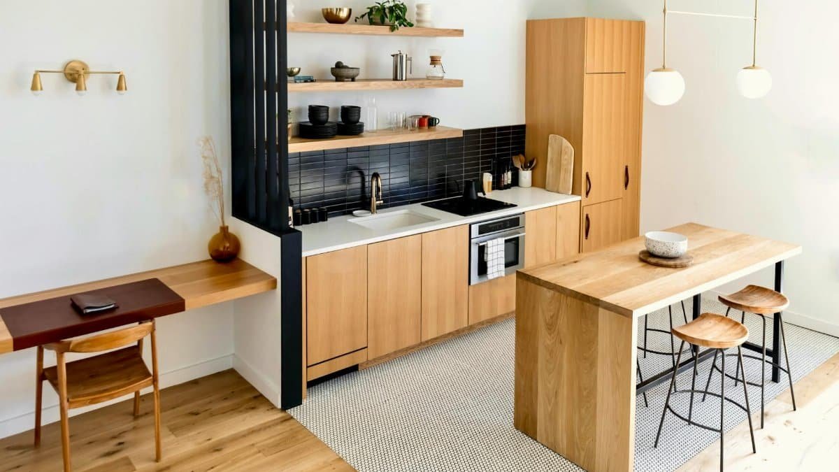 Light-filled modern kitchen interior with wooden furnishings and black accents.