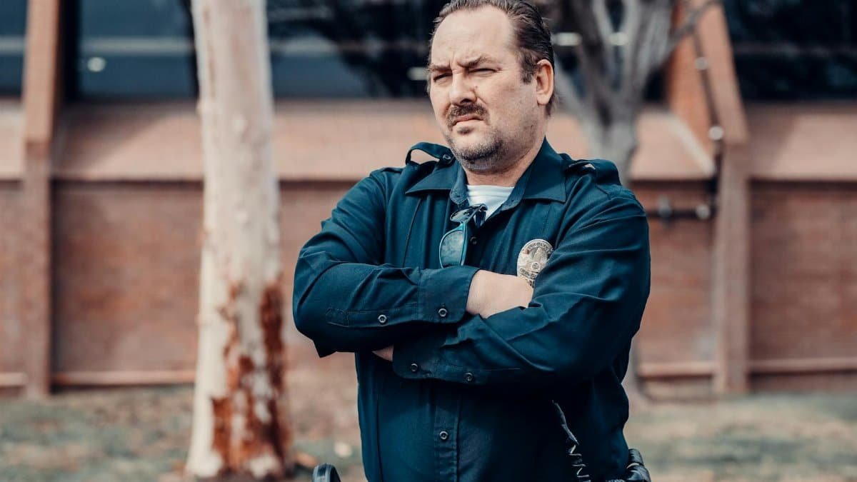 A determined police officer standing with arms crossed outside a building, showcasing authority.