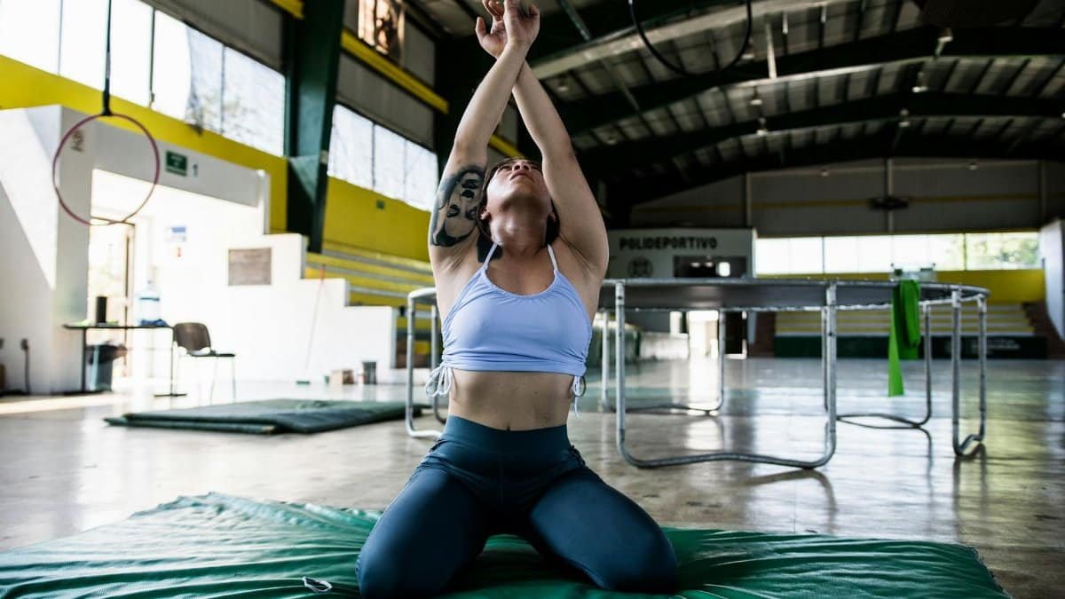 Focused gymnast in a sports hall performing exercises on a mat.