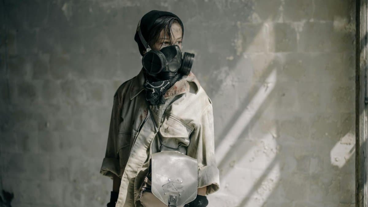 A young person with a gas mask stands in a dilapidated building, evoking a post-apocalyptic scene.