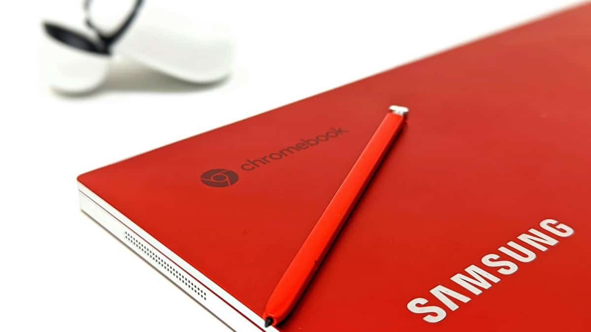 Close-up of a red Samsung Chromebook with stylus and earbuds case, highlighting sleek design.