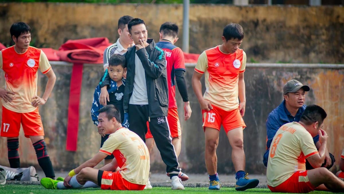 Amateur soccer players relax on the sidelines in Hà Nội, showcasing local sports culture.