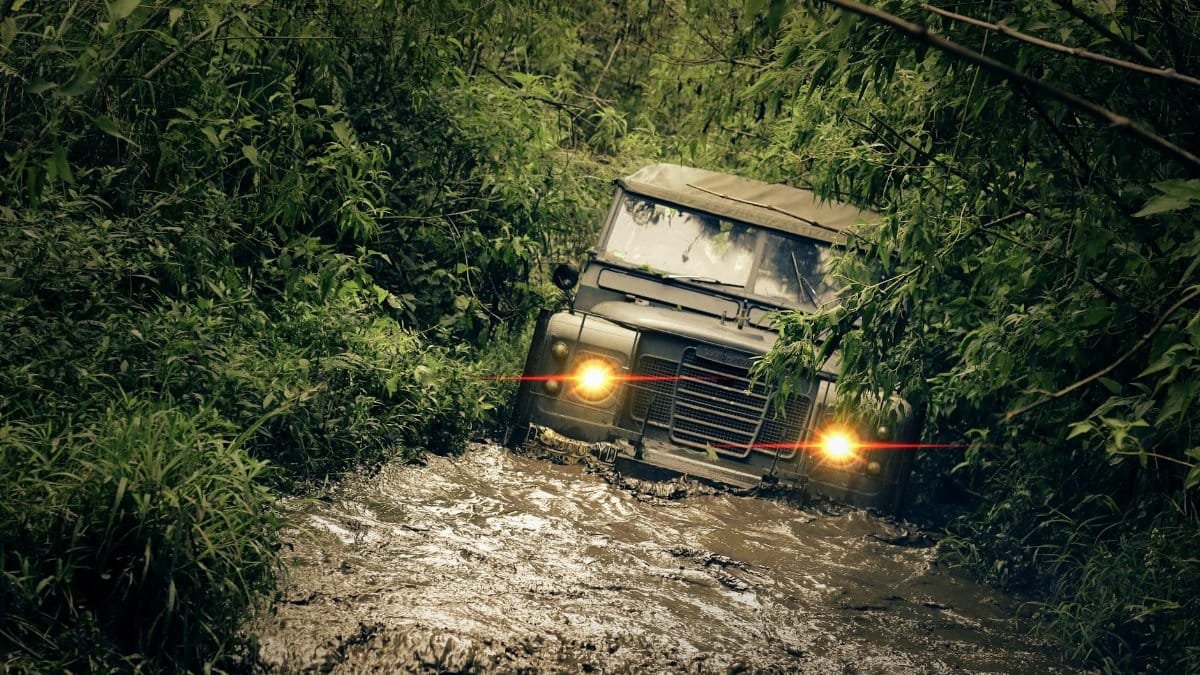 Jeep navigating through muddy jungle path, showcasing resilience and adventure.