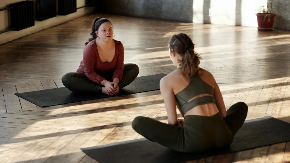 Two women practicing yoga indoors, embracing diversity and wellness.