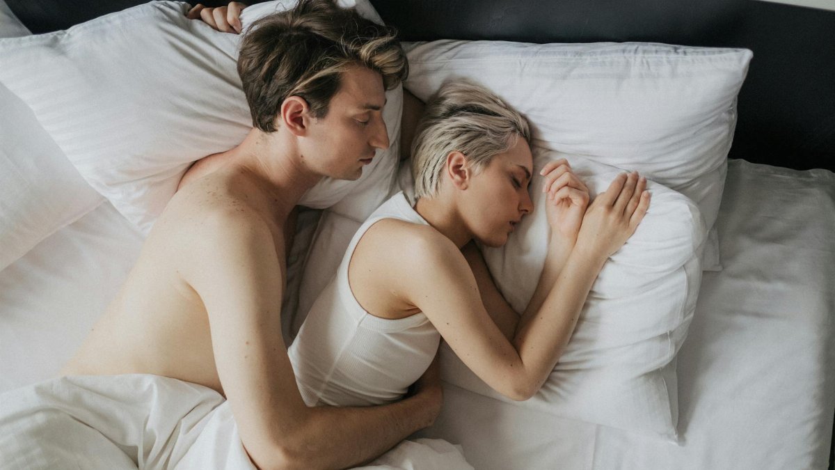 Couple embracing while sleeping peacefully in a cozy bedroom setting.