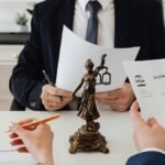 Legal professionals reviewing divorce documents in a law office with a Lady Justice statue.