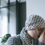 A woman wearing a polka dot scarf prays with hope, symbolizing strength and recovery during illness.