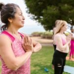 A senior woman practicing yoga with a group in a sunny park, promoting health and relaxation.