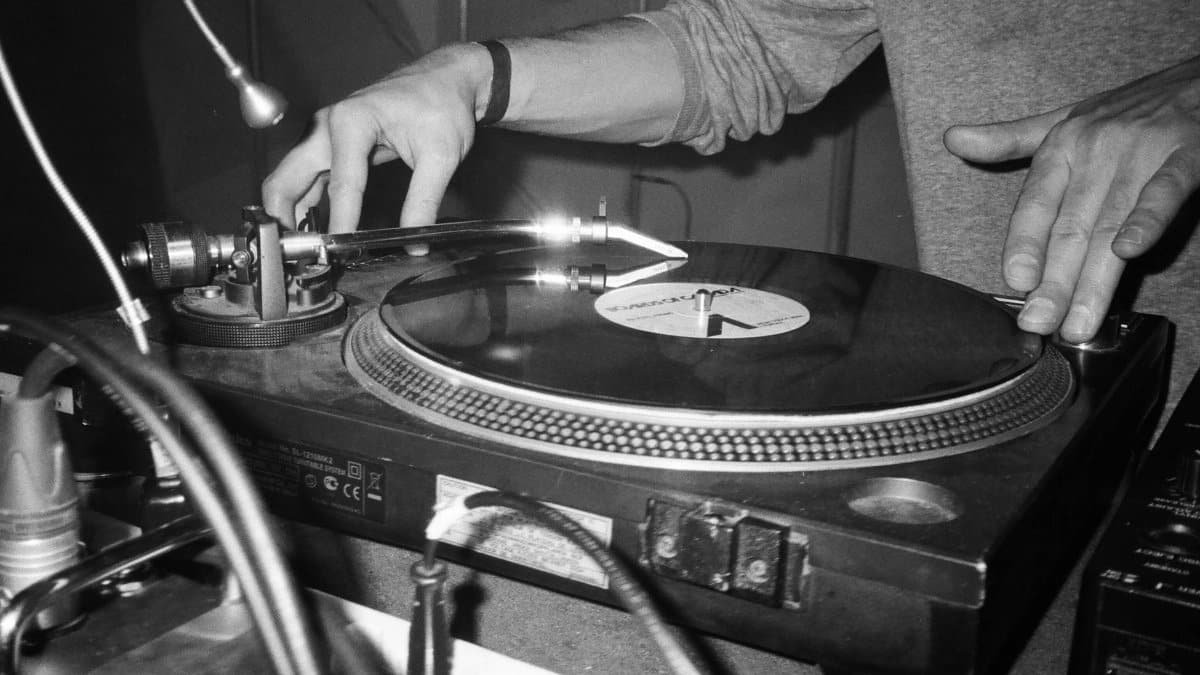Close-up of a DJ using a turntable to play vinyl records, showcasing music equipment.