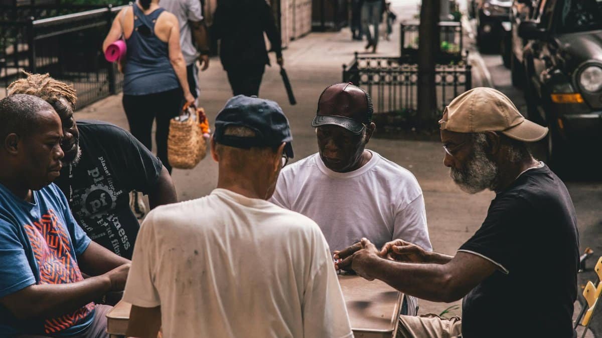A group of senior men enjoying a card game on a street table, showcasing leisure and community.