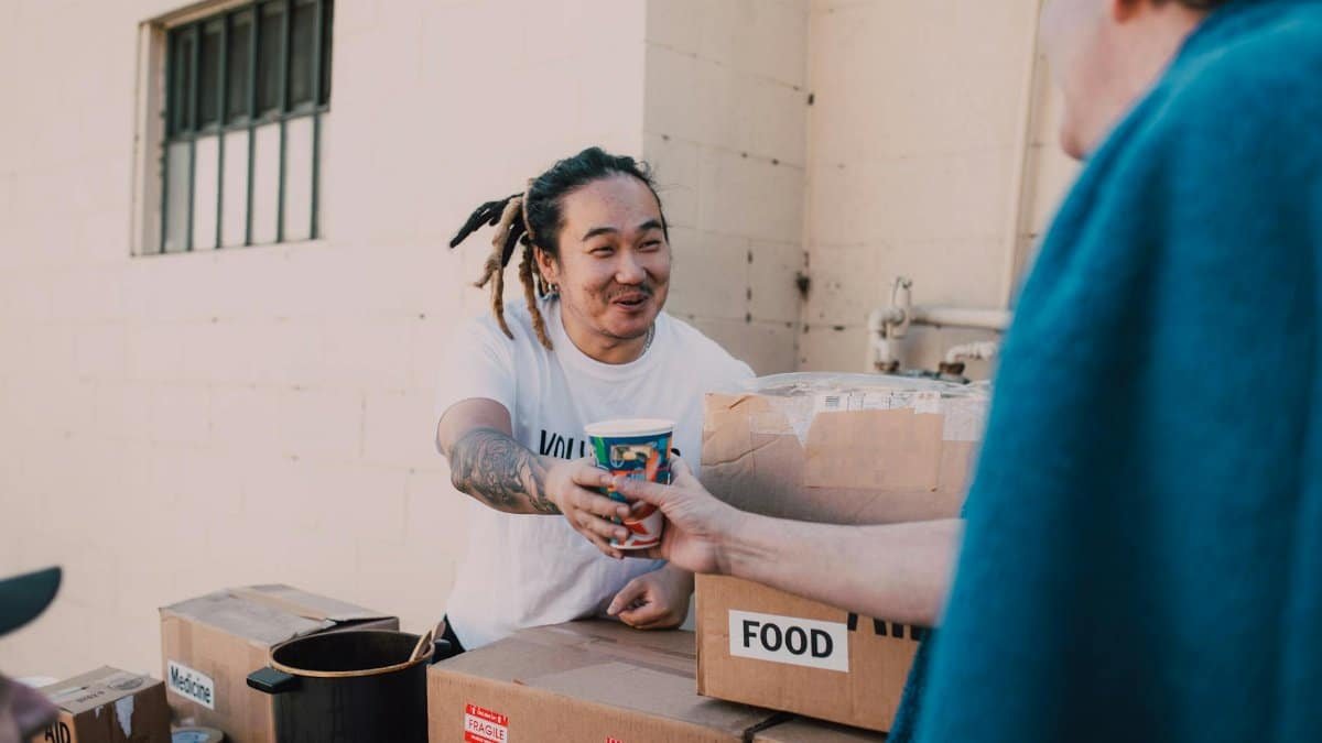 A volunteer handing out food and drinks at a charity event to support community causes.