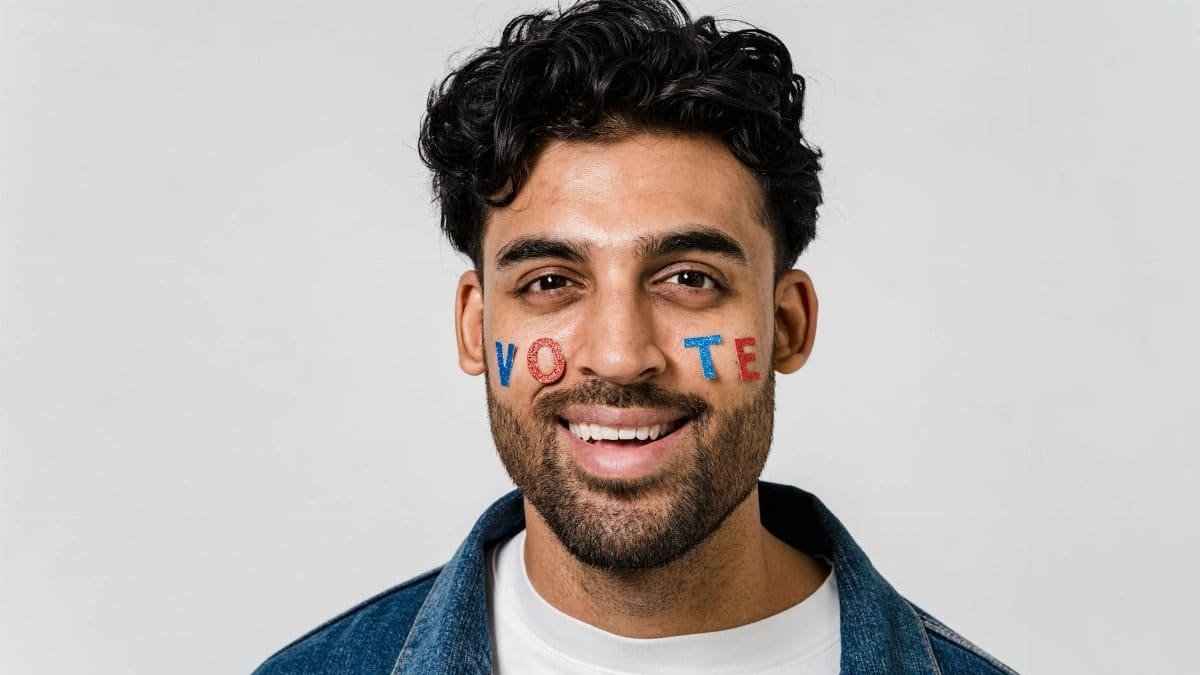 Portrait of a smiling man with the word 'vote' painted on his face, encouraging civic participation.