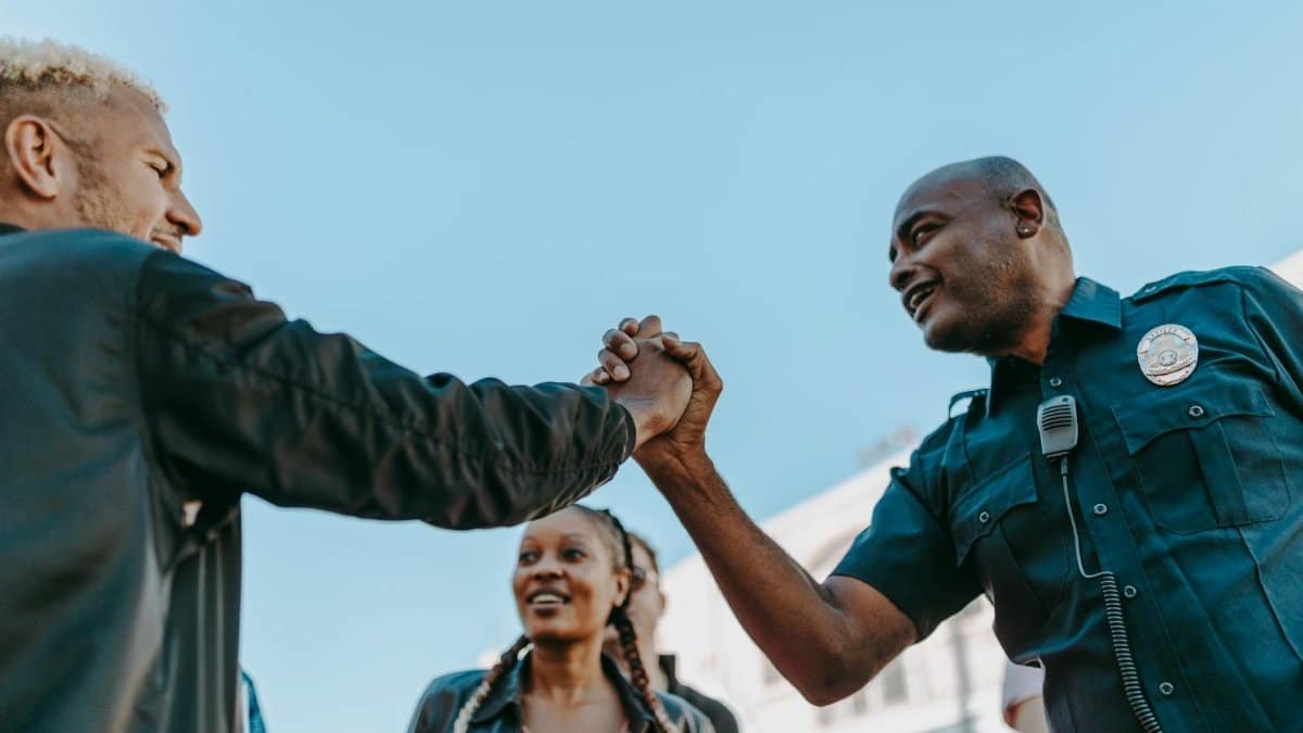 A friendly handshake between a police officer and a civilian during an outdoor community event.