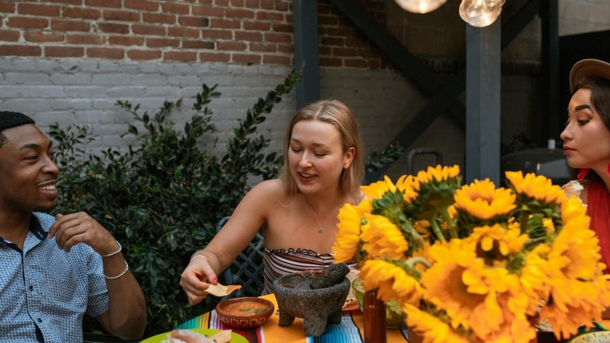 A group of diverse friends enjoying Mexican cuisine and vibrant sunflowers outdoors.