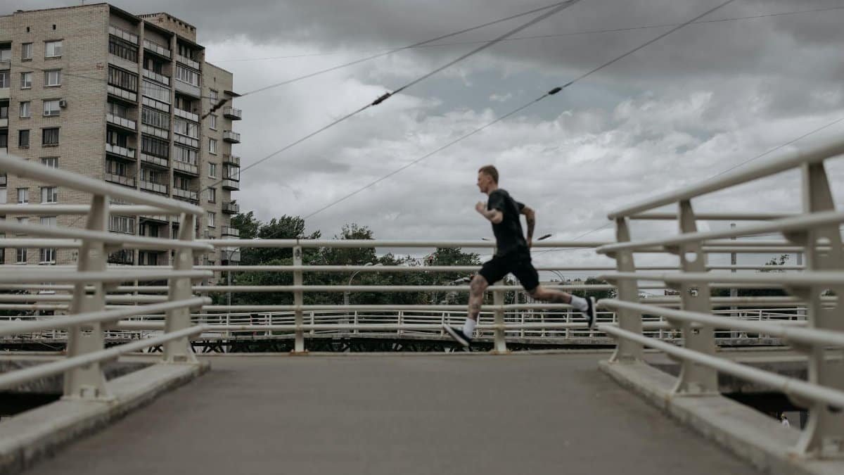 A man runs on a city bridge under cloudy skies, showcasing an active lifestyle.