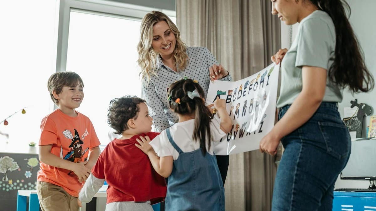 Preschool children and teachers enjoying an interactive alphabet learning session indoors.