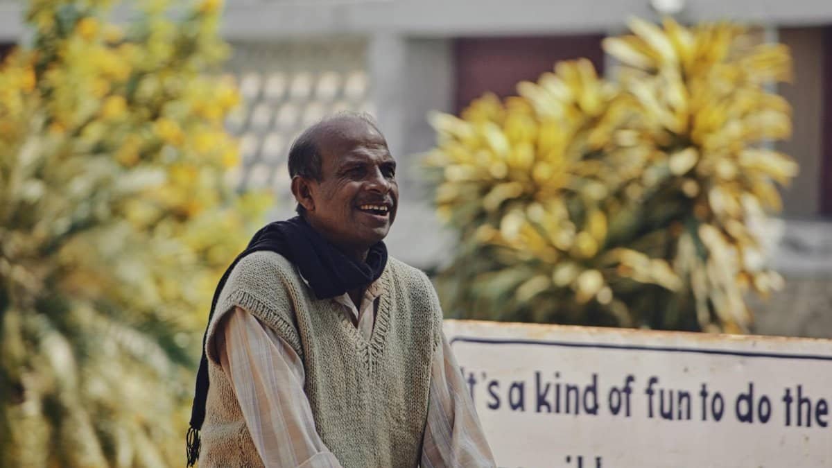Cheerful man standing outdoors, conveying joy and positivity with an inspirational sign.