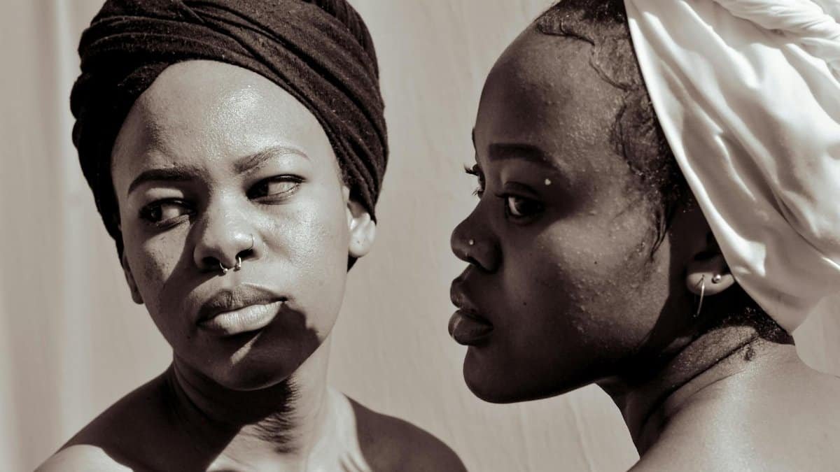 Elegant monochrome portrait showcasing two women in headwraps, emphasizing cultural style and expression.