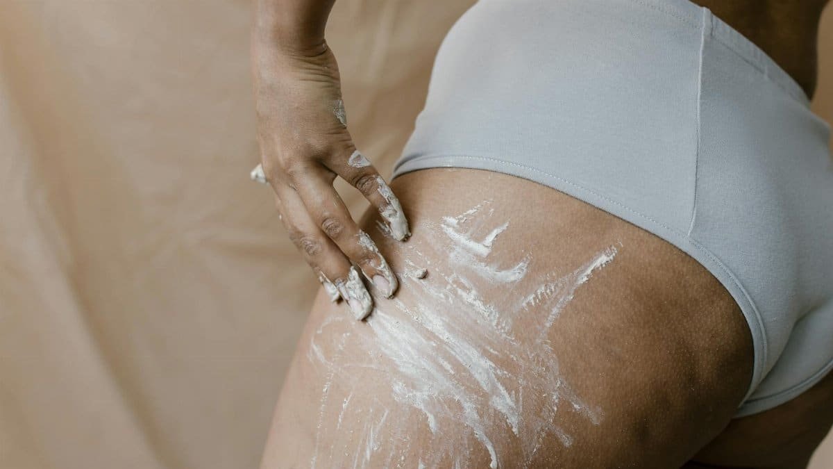 A person applying skincare clay on the leg in an intimate close-up, highlighting body care.