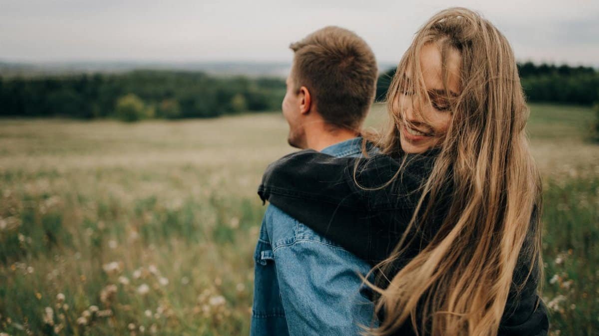 Happy couple embracing in a lush green field with a romantic atmosphere.