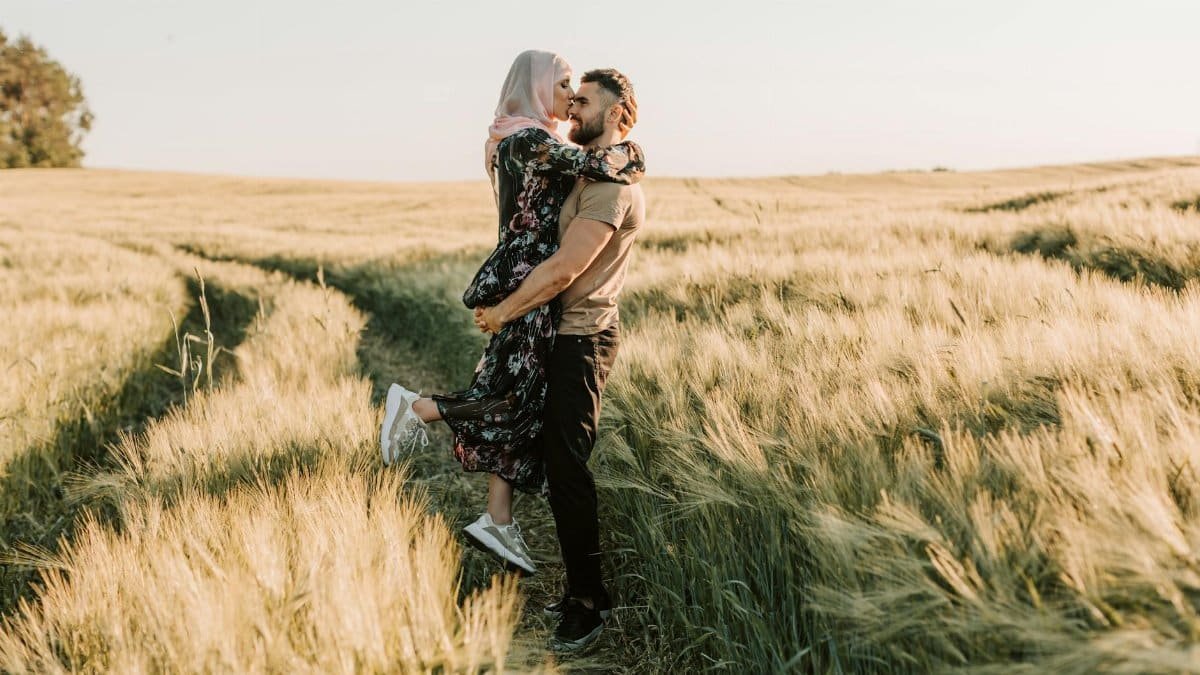 Happy couple embracing in a sunny wheat field during summer, symbolizing love and togetherness.