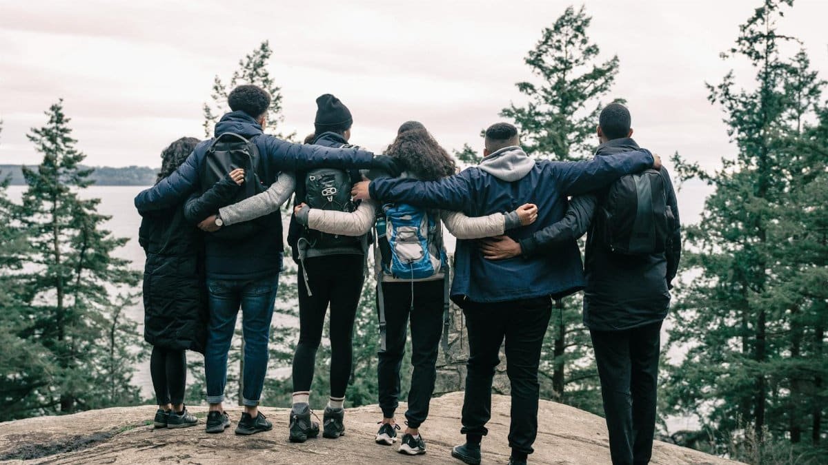 Back view of friends embracing on a scenic cliff, enjoying nature and friendship.