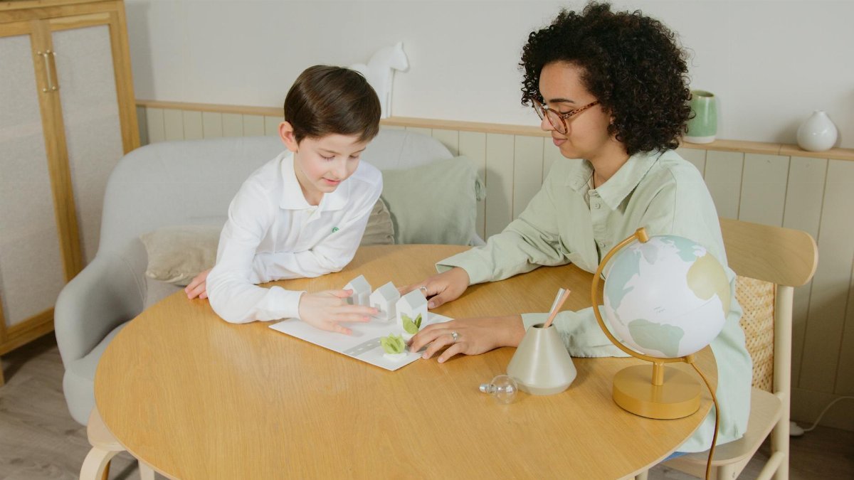 A teacher and student engage in learning with eco-friendly models in a cozy classroom setting.
