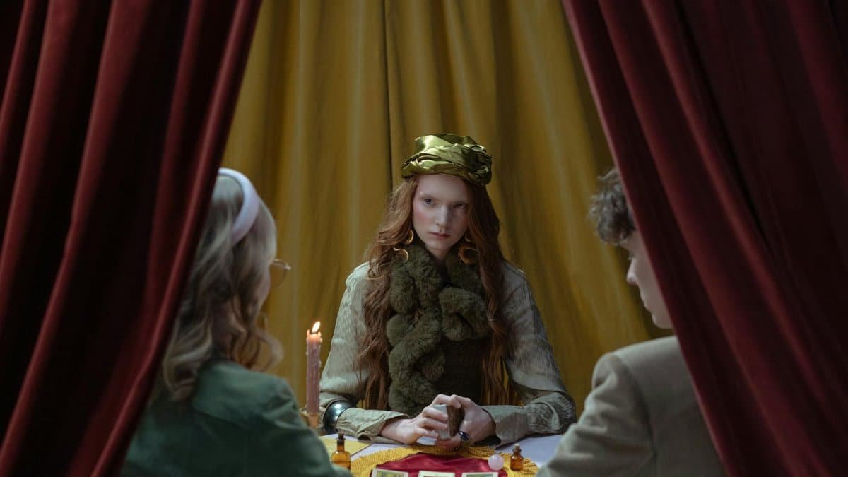 A mysterious fortune teller reads tarot cards for a couple in a mystical setting.
