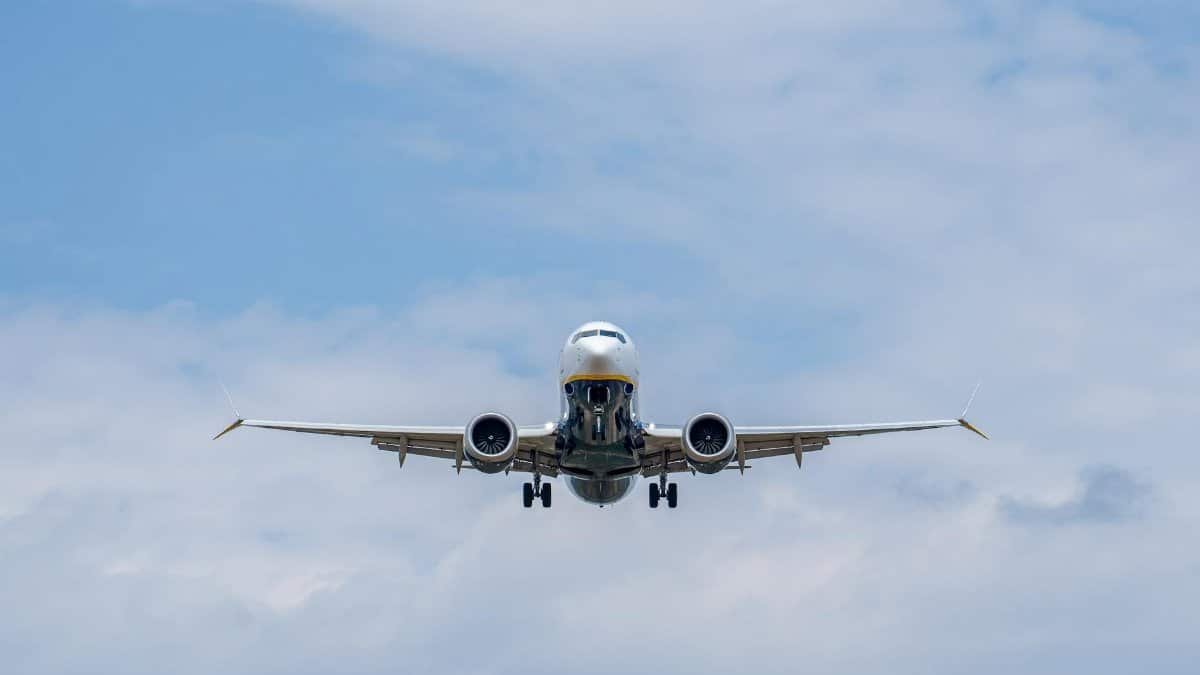 Airplane descending against a blue sky at Manises Airport in Spain, showcasing modern civil aviation.