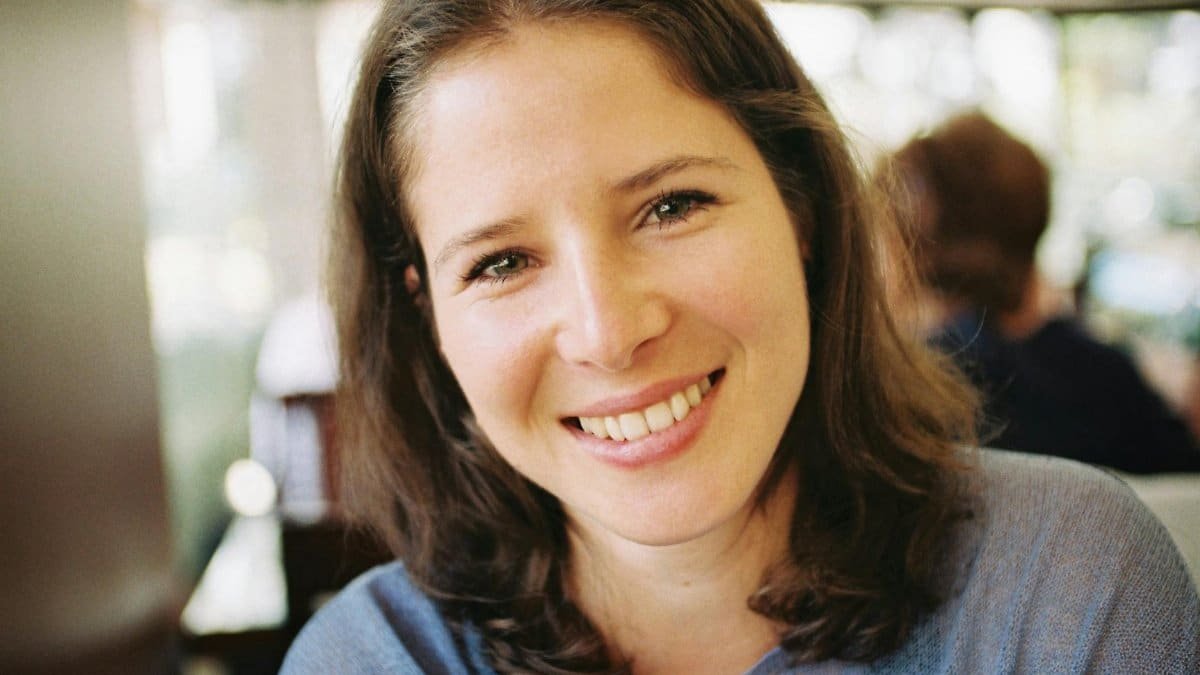 A candid portrait of a smiling woman indoors, capturing casual elegance and beauty.