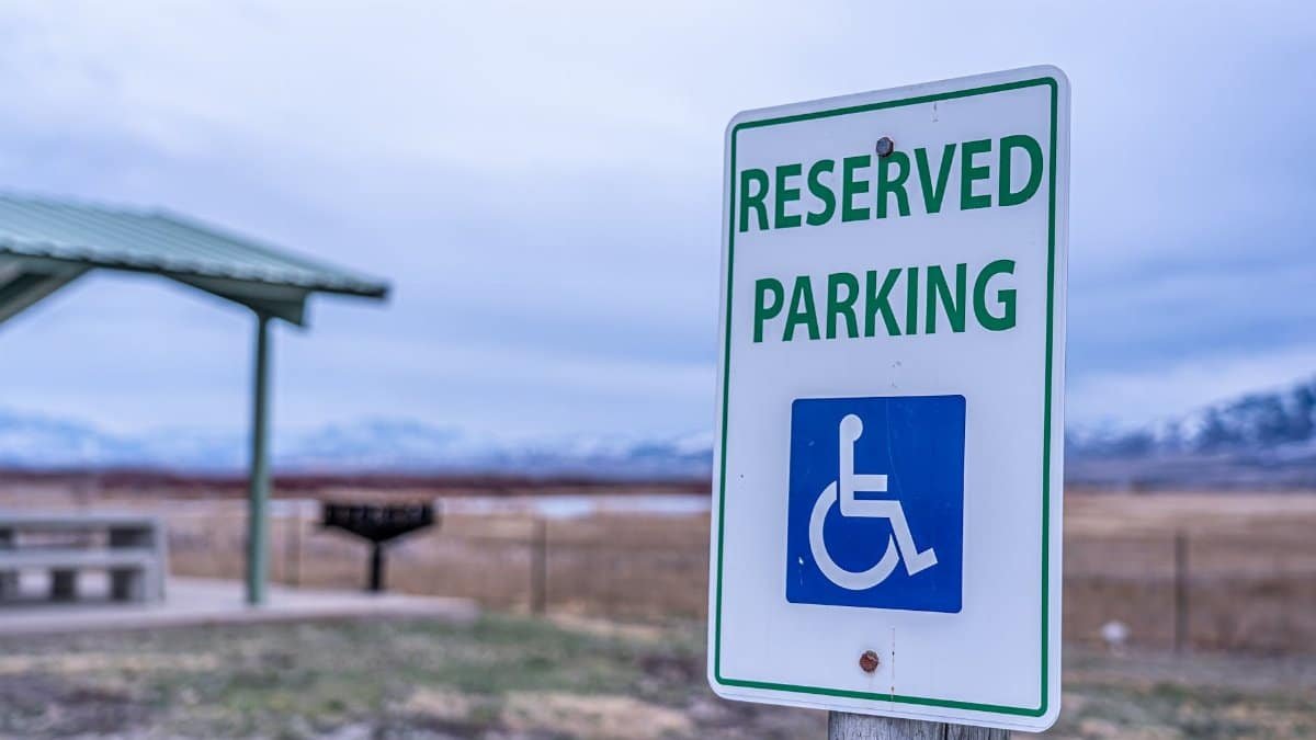 Close-up of reserved parking sign for handicapped access with mountain backdrop, outdoors.