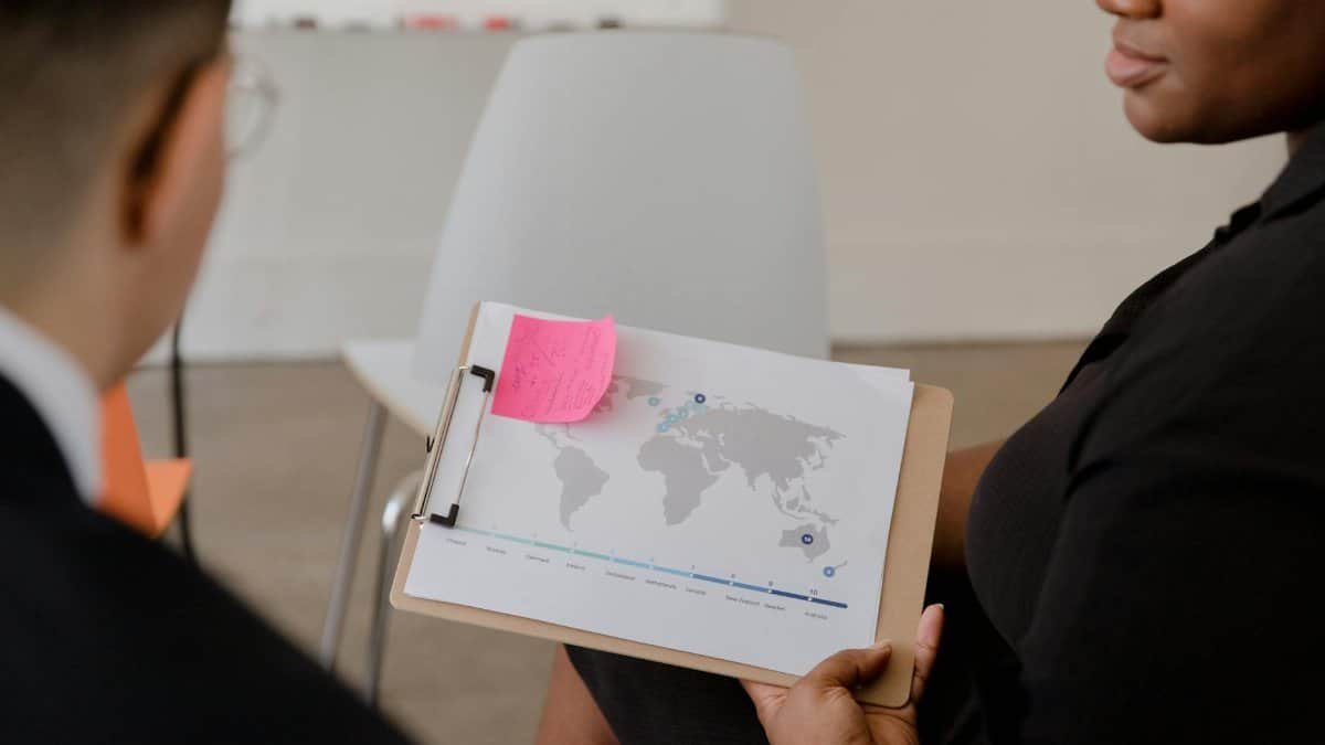 Professional discussion with world map and data visualization on a clipboard.