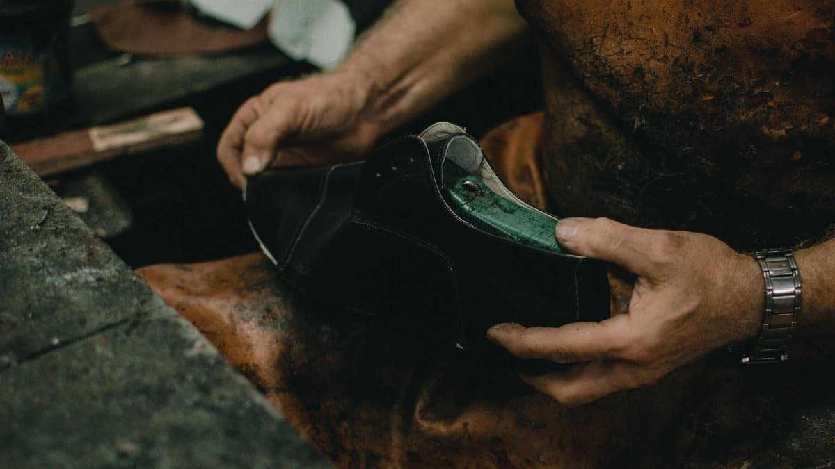Close-up of an artisan crafting a leather shoe by hand in a workshop.