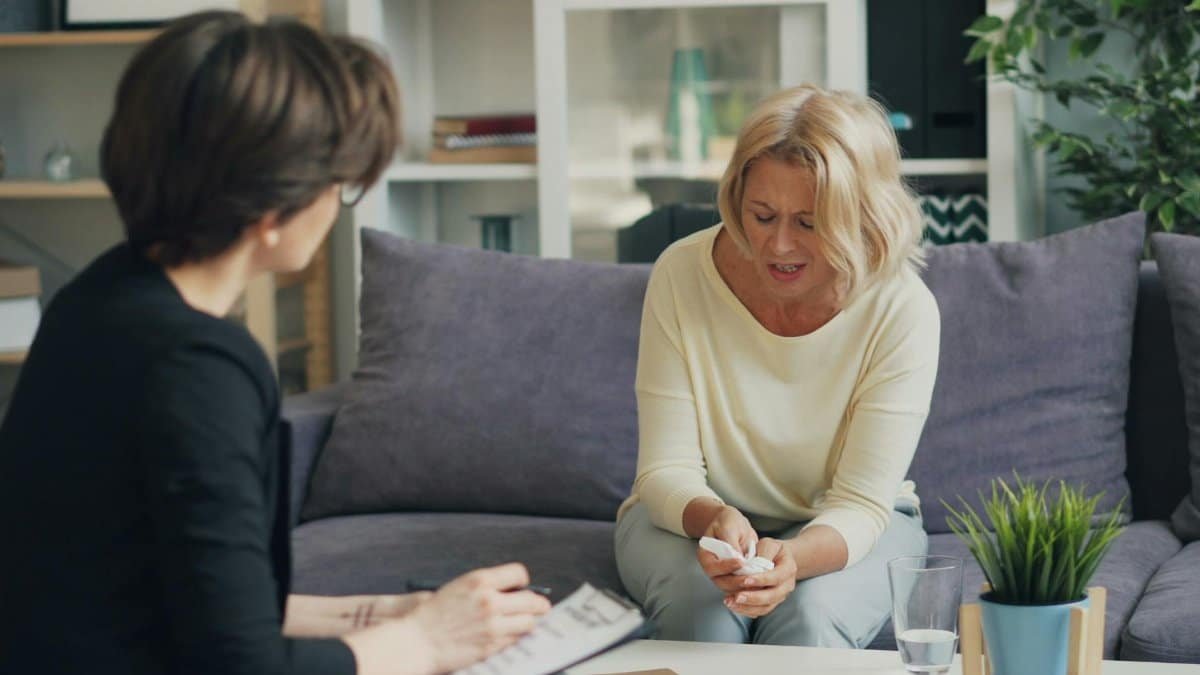 A woman in therapy session with a professional therapist, expressing emotions.