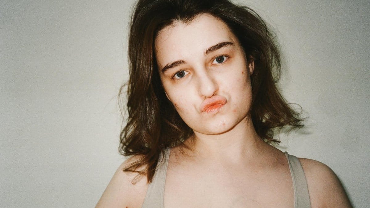 Close-up portrait of a young woman with pouting lips, expressing attitude.