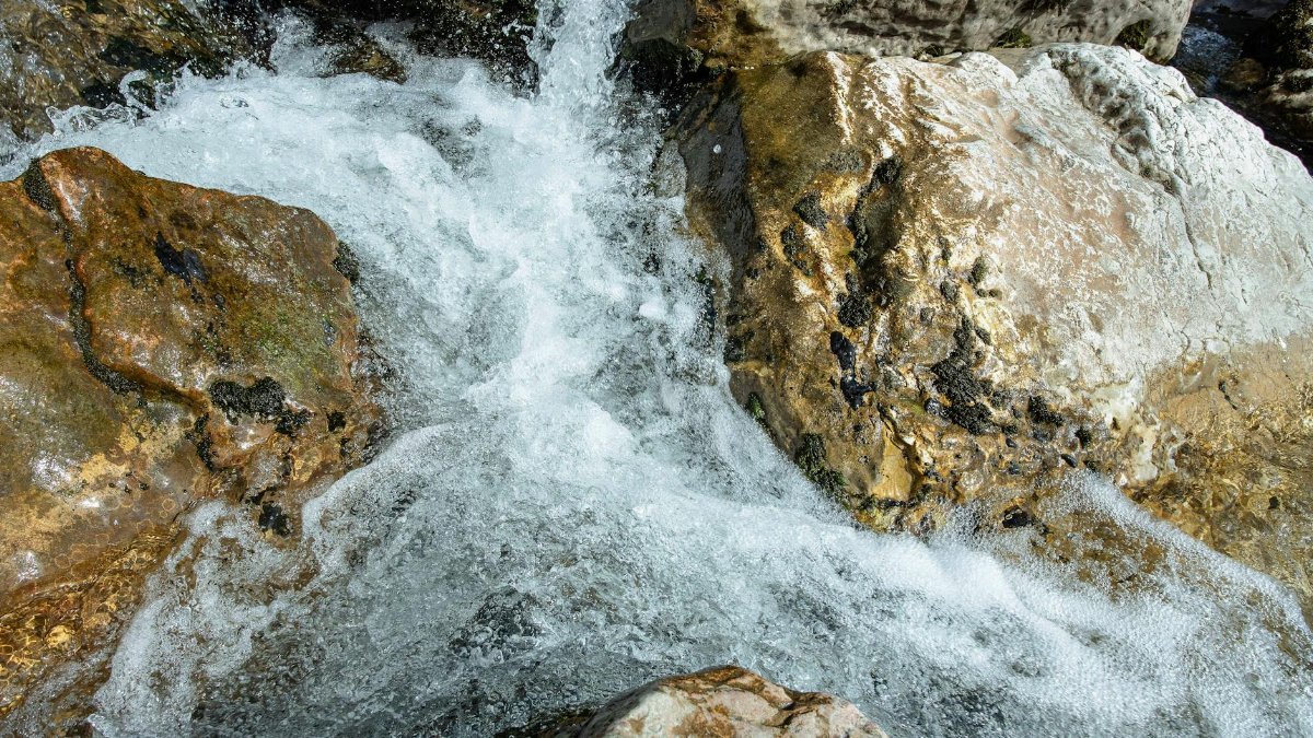 Captivating close-up of flowing water over rugged rocks in Bassano del Grappa, Italy. Ideal for nature and travel imagery.