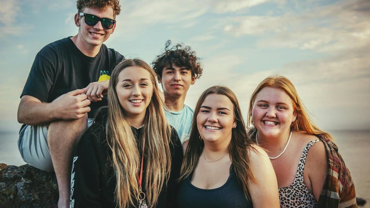 Happy young friends posing and smiling together at Avila Beach, California during a sunny day.