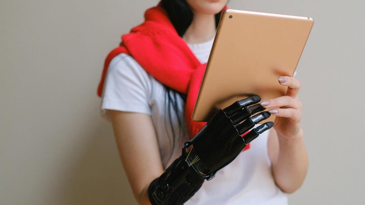 A woman with a bionic prosthetic arm uses a digital tablet indoors.