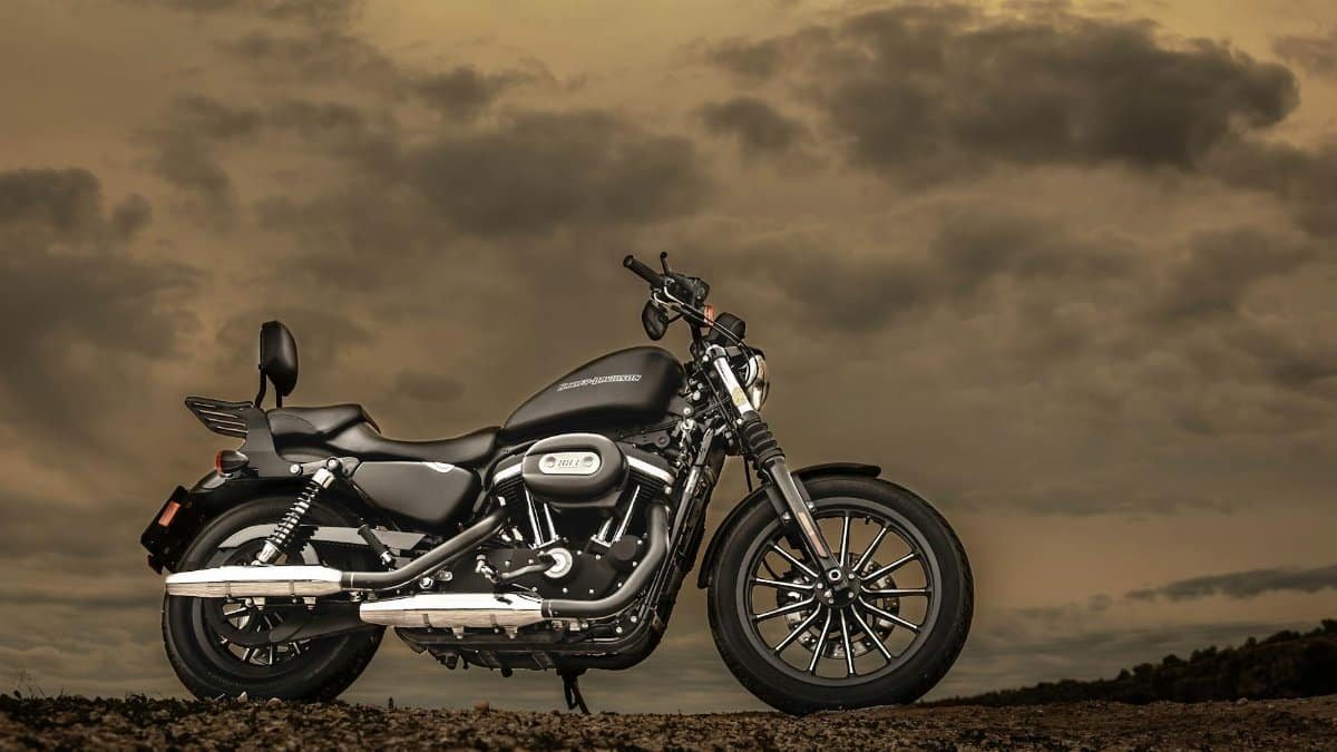 Harley Davidson motorcycle parked outdoors against a dramatic sunset sky, showcasing elegance and freedom.