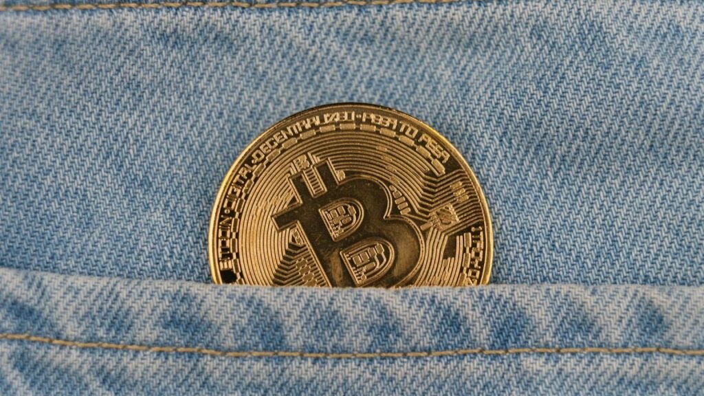 Close-up of a bitcoin coin in a denim pocket, symbolizing cryptocurrency and finance.