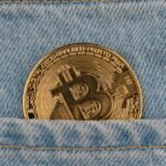 Close-up of a bitcoin coin in a denim pocket, symbolizing cryptocurrency and finance.