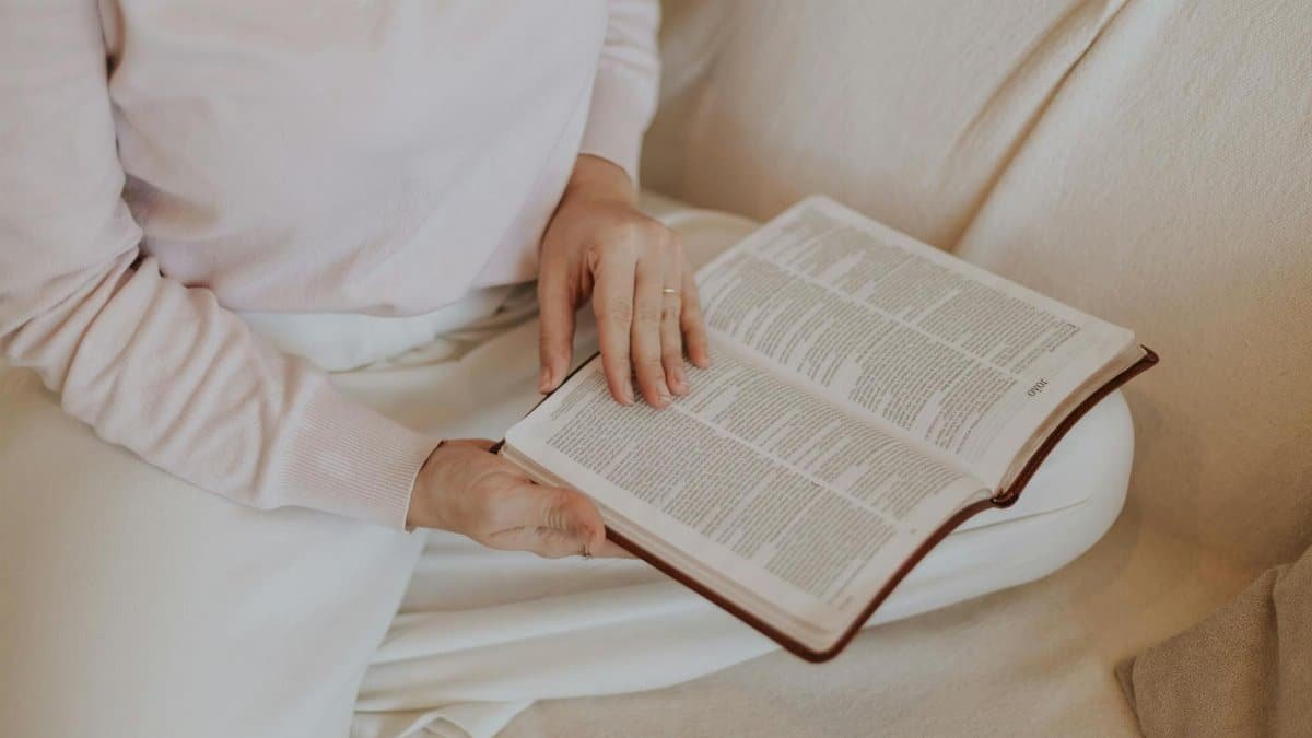 A woman reading a book comfortably on a couch, highlighting relaxation and self-care.