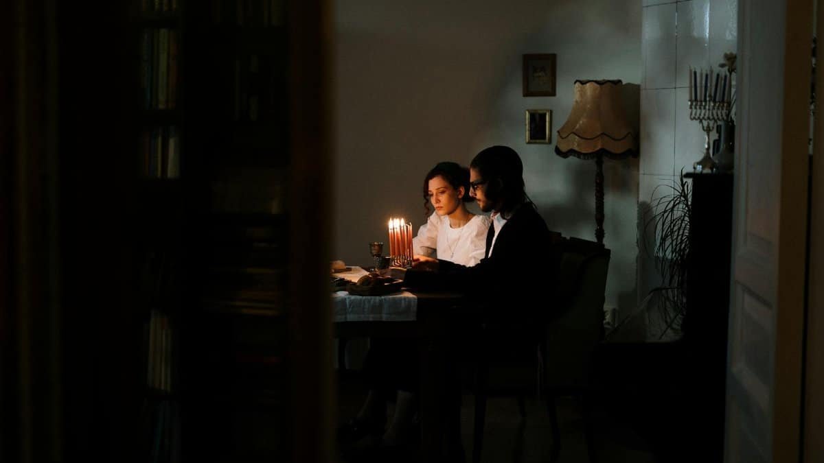 A couple celebrates Hanukkah by candlelight, enjoying a quiet evening at home.