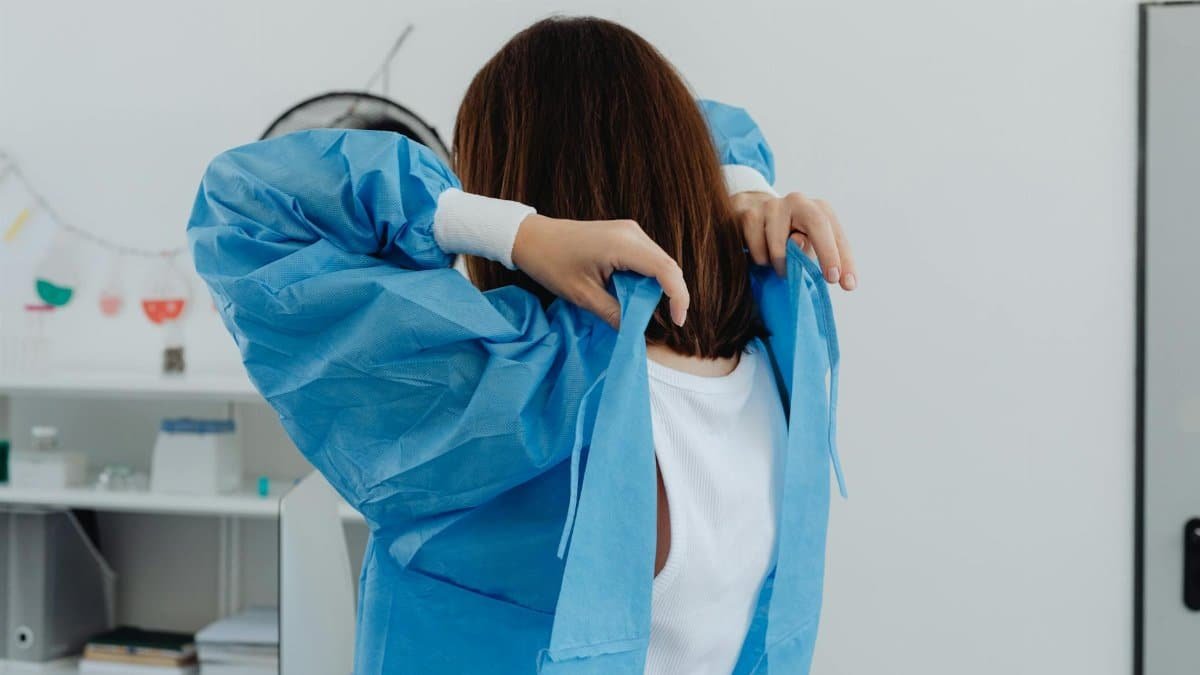Back view of female scientist wearing lab coat in a laboratory setting.