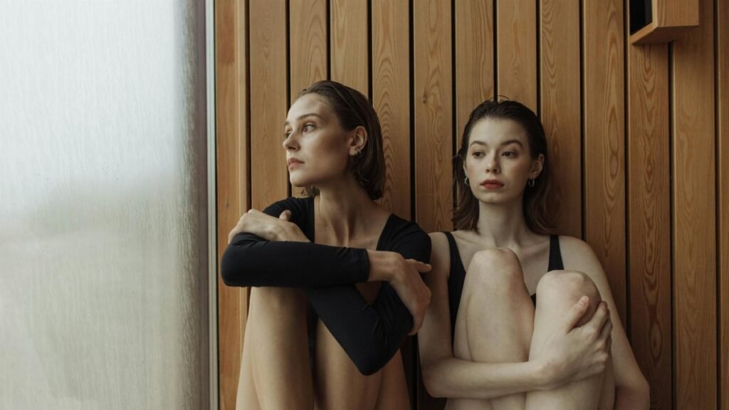 Two women in a sauna, relaxing and reflecting in a modern wellness environment.